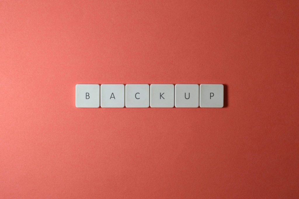 Free Close-up of keyboard keys spelling 'BACKUP' placed on a coral-colored surface. Stock Photo